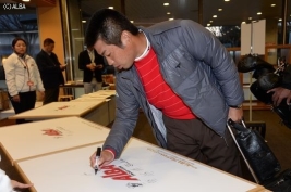 ボードにサインする池田勇太、参加プロが続々と来場(撮影:高木昭彦)